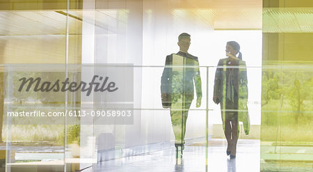 Silhouette businessman and businesswoman walking in modern office corridor