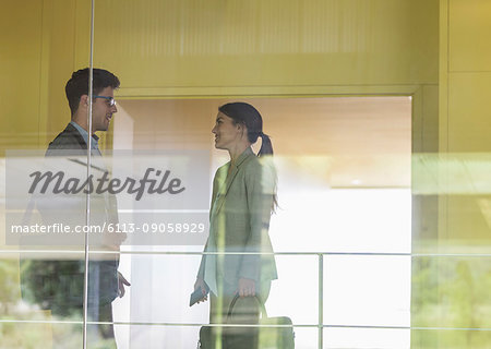 Businessman and businesswoman talking in modern office corridor