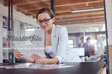 Female design professional reviewing photograph proofs in office