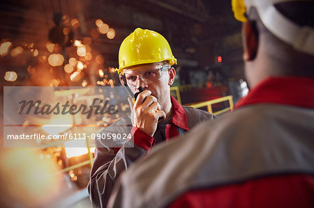 Steelworker talking, using walkie-talkie in steel mill