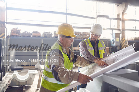 Steelworker and engineer reviewing blueprints in steel mill