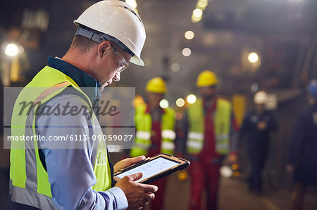 Steelworker using digital tablet in steel mill