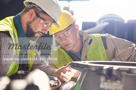 Steelworkers examining steel part in steel mill