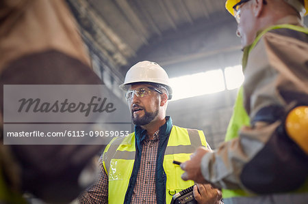 Supervisor talking to steelworkers in steel mill