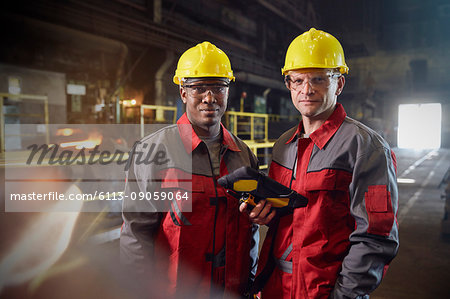 Portrait confident steelworkers with digital tablet in steel mill