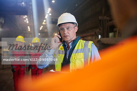Steelworker supervisor talking on smart phone in steel mill