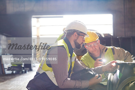 Steelworkers examining steel part in steel mill