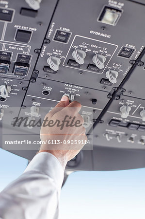 Pilot adjusting control instruments in airplane cockpit