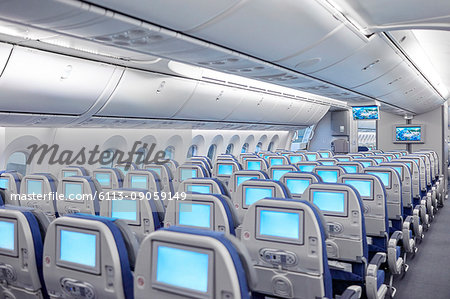 Rows of seats with entertainment screens on airplane