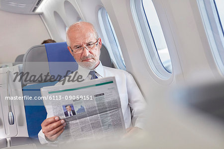 Businessman reading newspaper on airplane