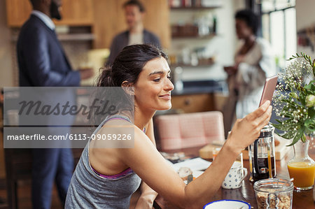 Young woman texting with smart phone at breakfast table