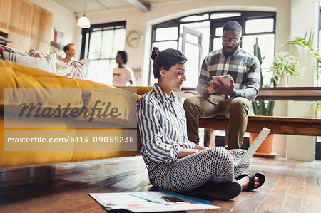 Female freelancer working at laptop on living room floor