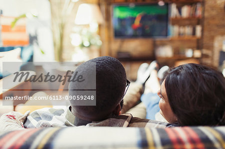 Young couple relaxing, watching TV on living room sofa