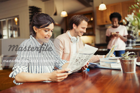 Woman reading newspaper at dining table