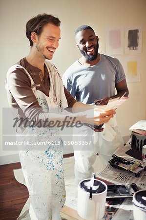 Gay couple viewing paint swatches, painting living room