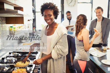 Portrait smiling woman cooking scrambled eggs at stove in kitchen