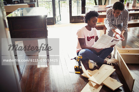 Women reading instructions, assembling furniture