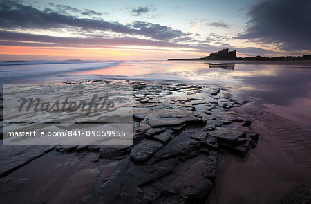 View towards Bamburgh Castle at sunrise from Bamburgh Beach, Bamburgh, Northumberland, England, United Kingdom, Europe