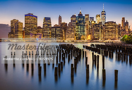 Lower Manhattan skyline, New York skyline, exposed wooden pier stumps, at night, East River, New York, United States of America, North America