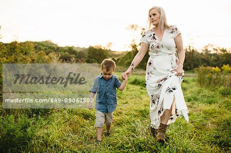 Mother and son walking on grass holding hands