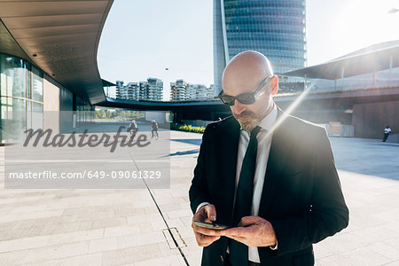 Mature businessman outdoors, using smartphone