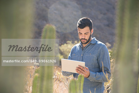 Young male hiker looking at digital tablet in sunlit valley, Las Palmas, Canary Islands, Spain