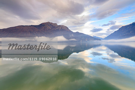 Mountains reflected in Lake Mezzola at dawn shrouded by mist, Verceia, Chiavenna Valley, Lombardy, Italy, Europe