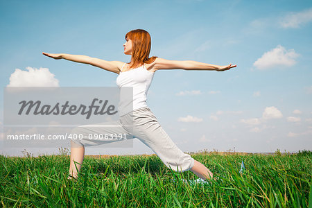 Young girl doing yoga in the park over blue sky