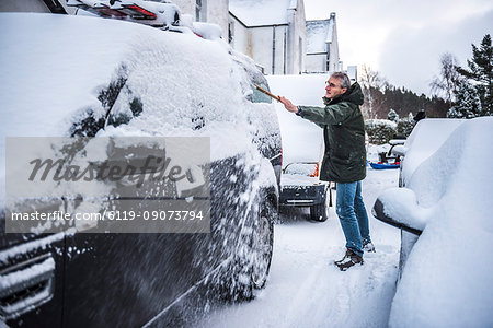 Removing snow from a car, Cairngorms National Park, Scotland, United Kingdom, Europe