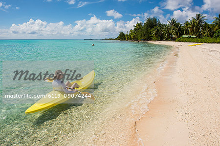 Woman kayaking in the turquoise waters of Tikehau, Tuamotus, French Polynesia, Pacific