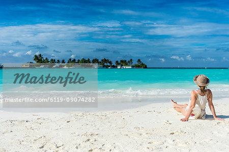 Woman sitting on a white sand beach enjoying the turquoise water, Sun Island Resort, Nalaguraidhoo island, Ari atoll, Maldives, Indian Ocean, Asia