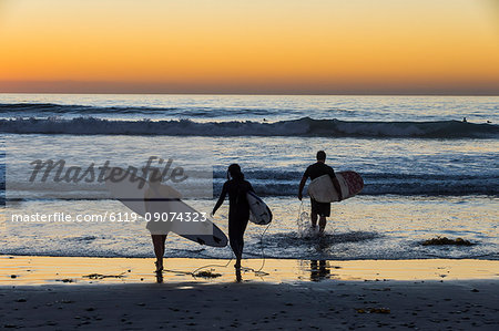 Surfers walking with their surfboards in the ocean at sunset, Del Mar, California, United States of America, North America