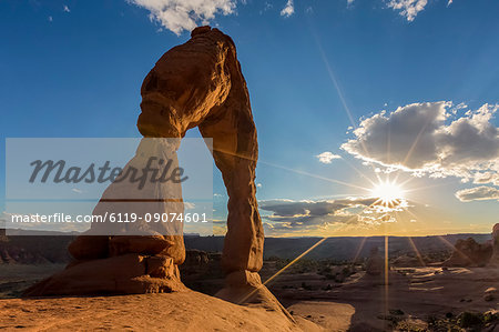 Delicate Arch with sun and clouds at golden hour, Arches National Park, Moab, Grand County, Utah, United States of America, North America