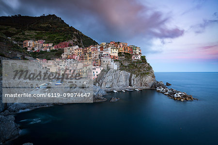 The clouds over Manarola light up with the colours of sunset during a long exposure, Manarola, Cinque Terre, UNESCO World Heritage Site, Liguria, Italy, Europe