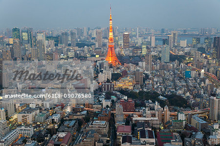 Cityscape of large city with illuminated skyscraper at dusk.