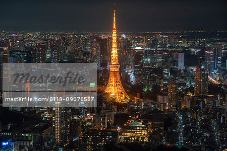 Cityscape of large city with illuminated skyscraper at night.