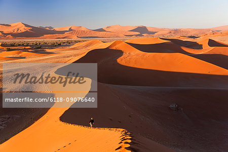 Aerial view of desert landscape, distant view of person walking along ridge of sand dune.
