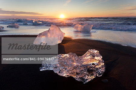 Glassy pieces of ice on volcanic black sand beach at sunrise, near Jokulsarlon Lagoon, South Iceland, Polar Regions
