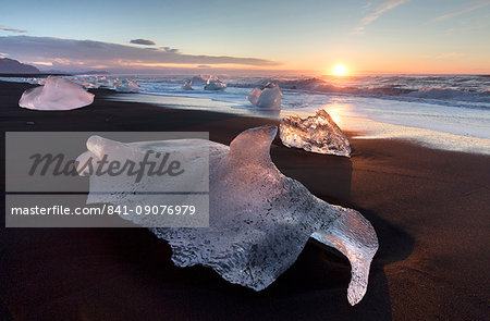 Glassy pieces of ice on volcanic black sand beach at sunrise, near Jokulsarlon Lagoon, South Iceland, Polar Regions