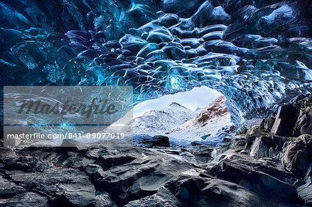 View from inside ice cave under the Vatnajokull Glacier towards snow covered mountains, near Jokulsarlon Lagoon, South Iceland, Polar Regions