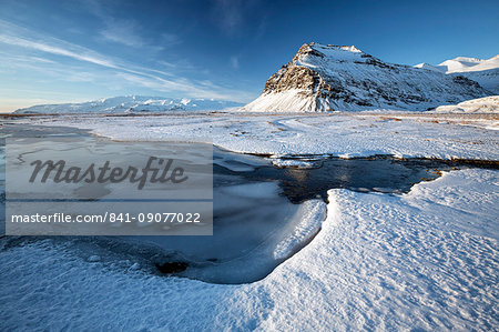 Snow covered landscape in winter with frozen pool, mountain and Vatnajokull Glacier, near Jokulsarlon Lagoon, South Iceland, Polar Regions