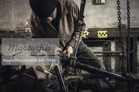 Mechanic repairing dismantled vintage motorcycle in workshop Mechanic repairing dismantled vintage motorcycle in workshop