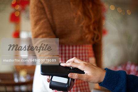 Customer in cafe making contactless payment with mobile phone