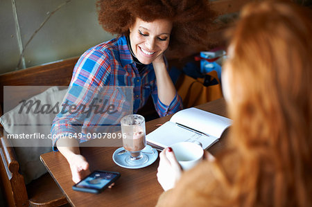 Friends with smartphone relaxing in cafe