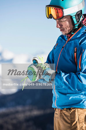 Mature man wearing skiwear, putting on ski gloves
