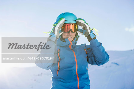 Portrait of skier, adjusting goggles