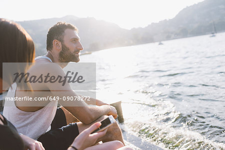 Young couple sitting on waterfront, Lake Como, Lombardy, Italy