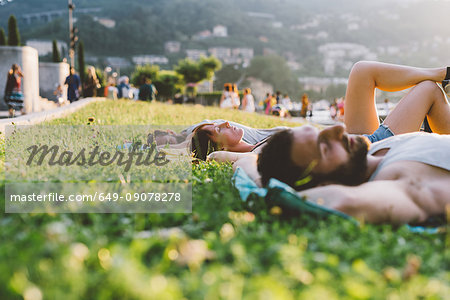 Young couple lying on waterfront grass, Lake Como, Lombardy, Italy