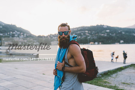 Portrait of young male hipster with backpack at lake Como, Lombardy, Italy