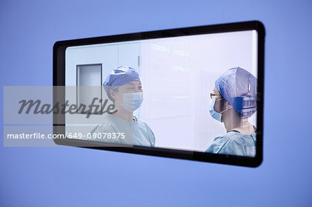 Window view of two female surgeons having discussion in maternity ward operating theatre